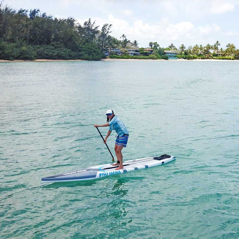 A woman paddling the cadence paddleboard on the sea with beach homes in the background
