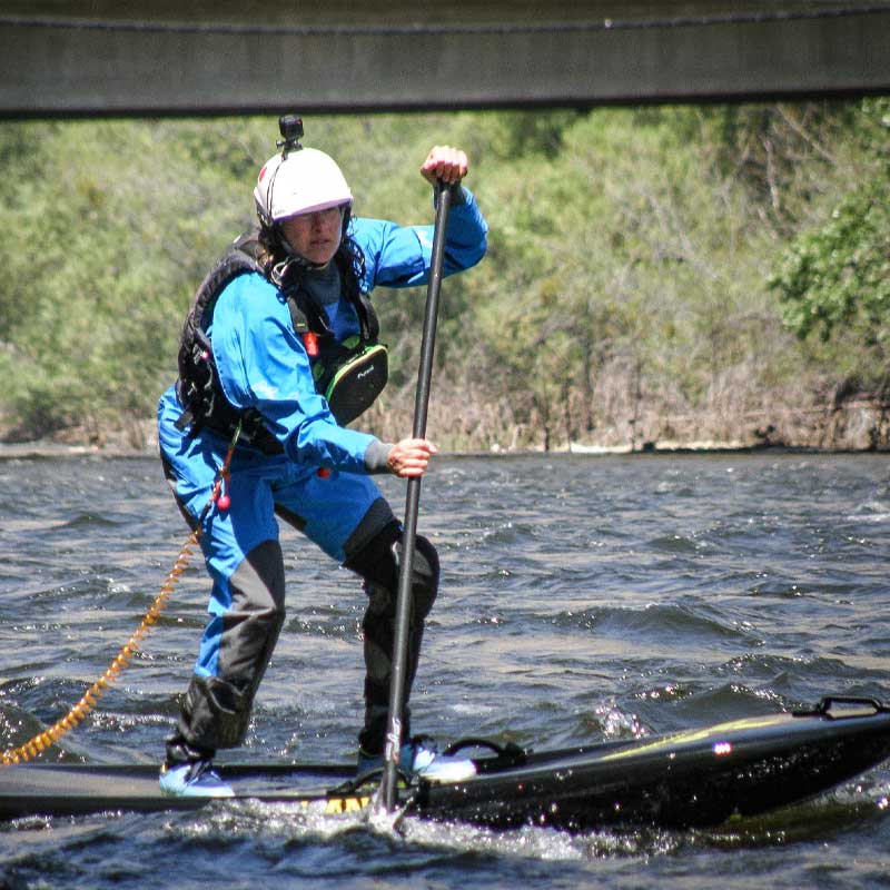 A woman whitewater paddlebaording on a river