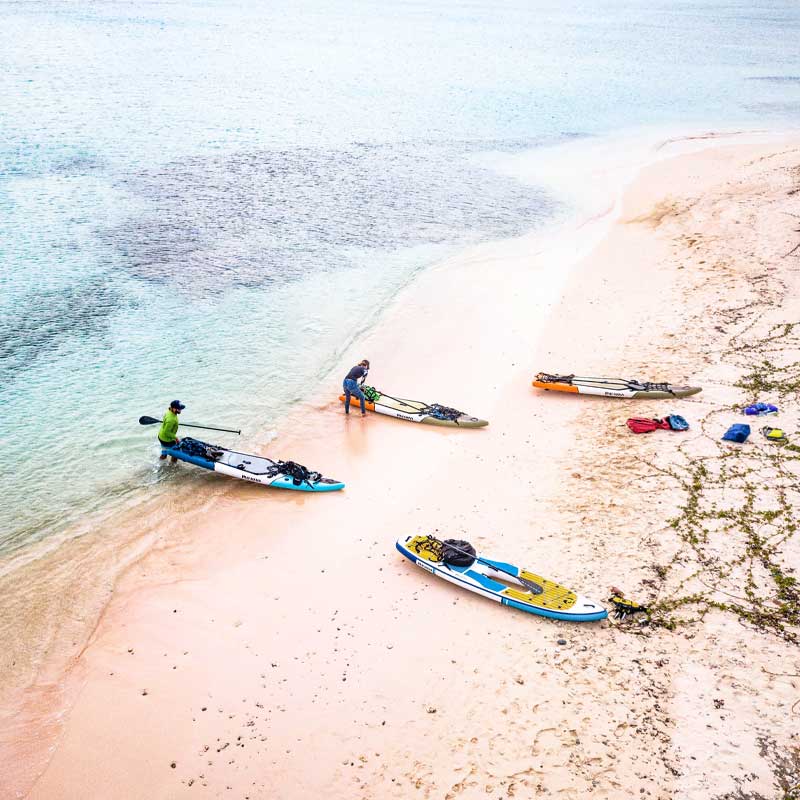 Pulling inflatable paddleboards onto the pink sandy beach in barbuda