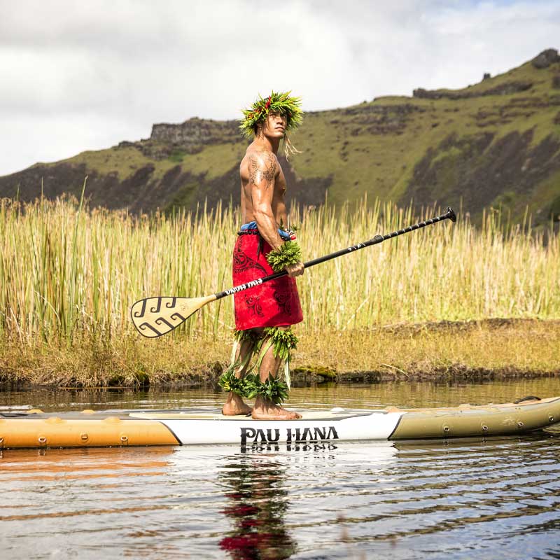a guy standing on the Endurance air inflatable paddleboard on a lake with reeds in the background