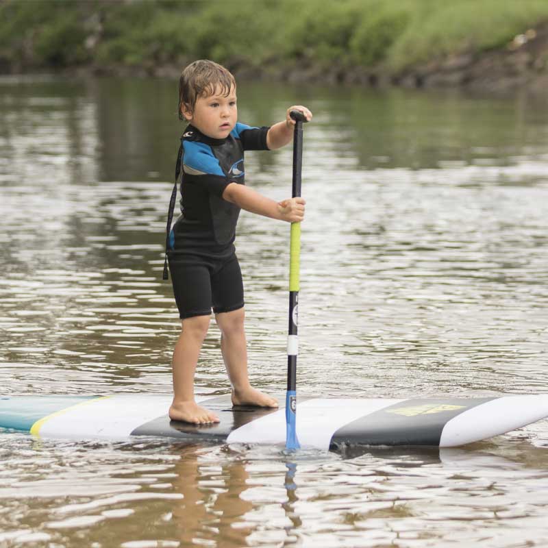 A kid paddling a stand up paddleboard on a river