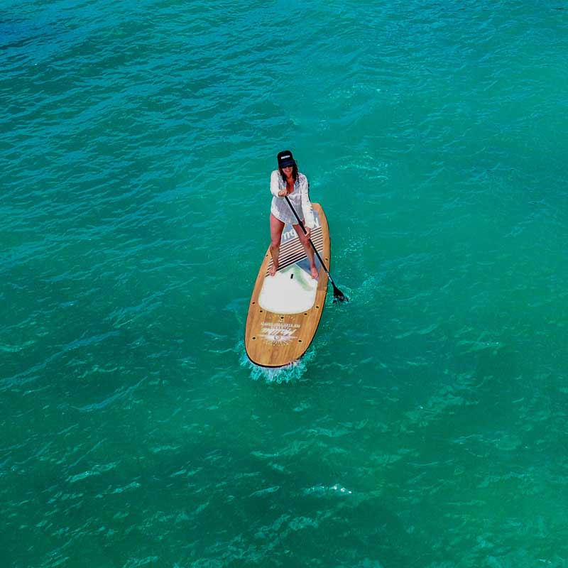 an aerial image of a woman paddling the malibu classic paddleboard on the ocean