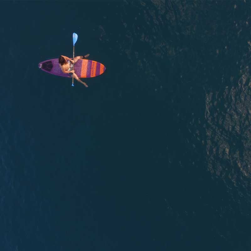 an aerial image of a guy sat on the carve pro paddleboard in the ocean