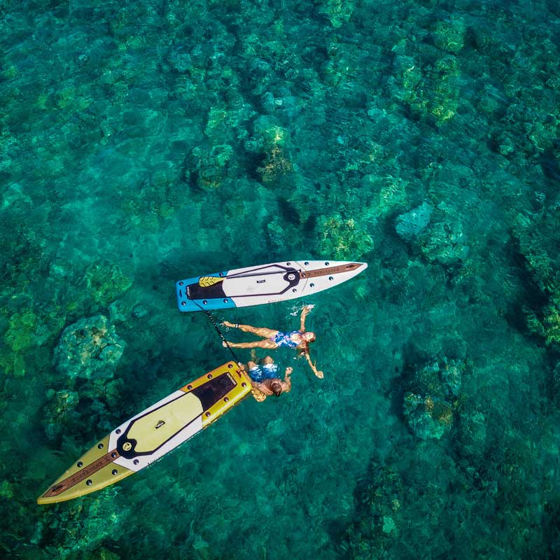 two people floating in the ocean next to two paddleboard