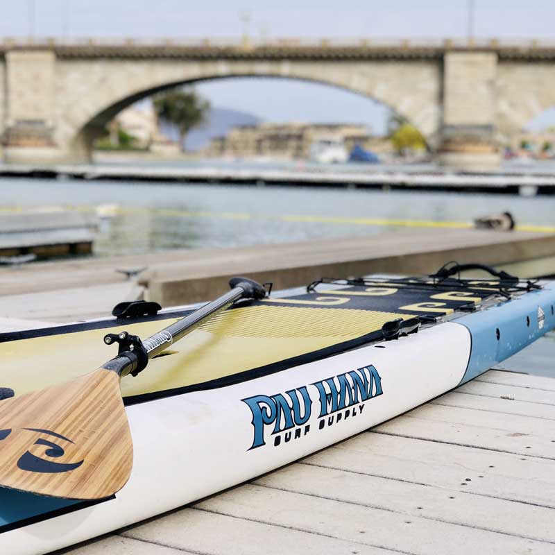 the endurance xl paddleboard pulled onto a dock with the carbon teak paddle on top of it