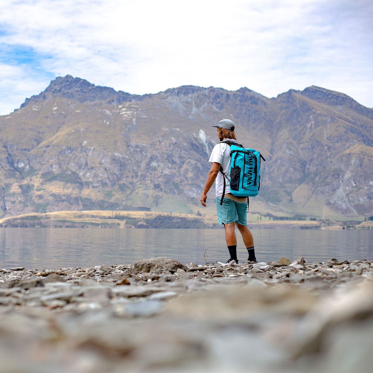 A man hiking with an inflatable stand up paddleboard in a backpack by a lake