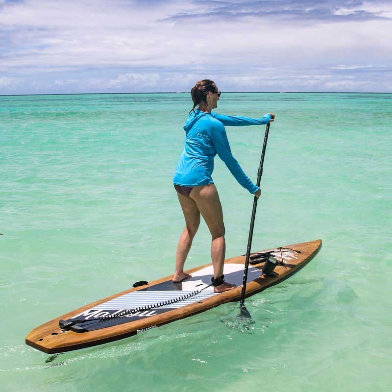 a woman paddling the malibu tour paddleboard on green water