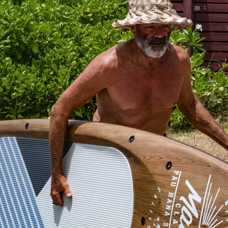 a man carrying the malibu touring paddleboard wearing a straw hat