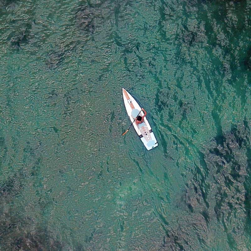 an aerial image of a girl paddling the minisport paddleboard on the sea