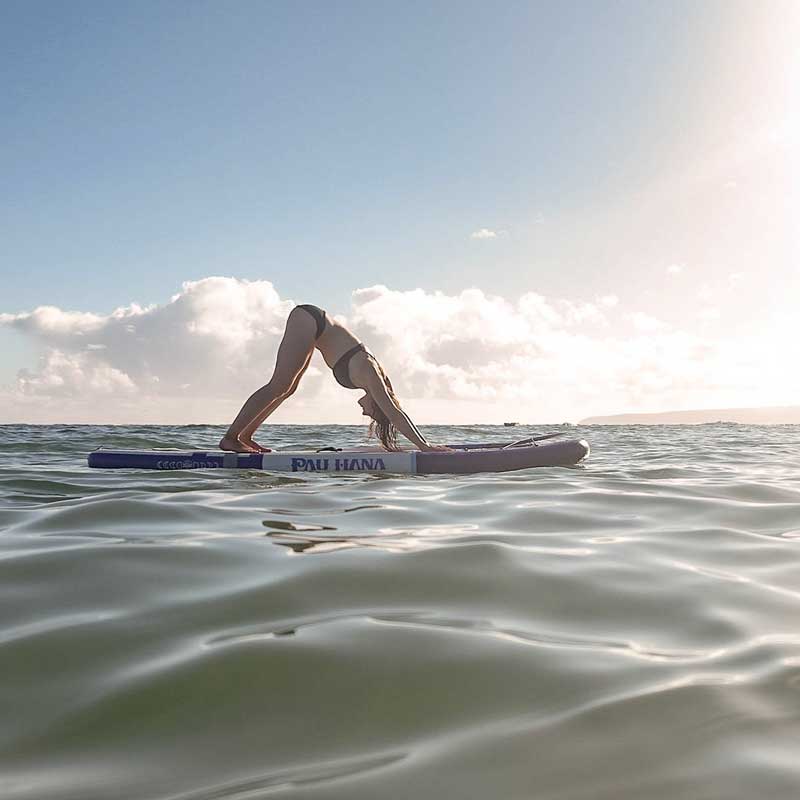 A woman doing yoga on the moonmist inflatable paddleboard on the ocean
