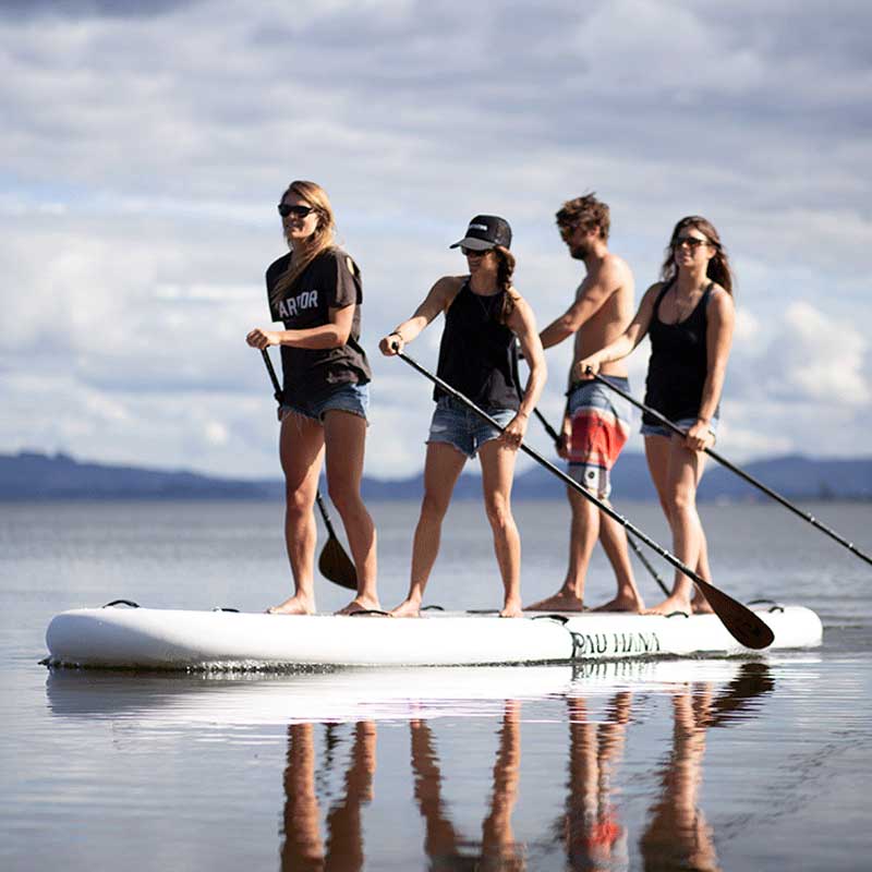 a group of friends paddling the oahu nui giant inflatable paddleboard on a lake