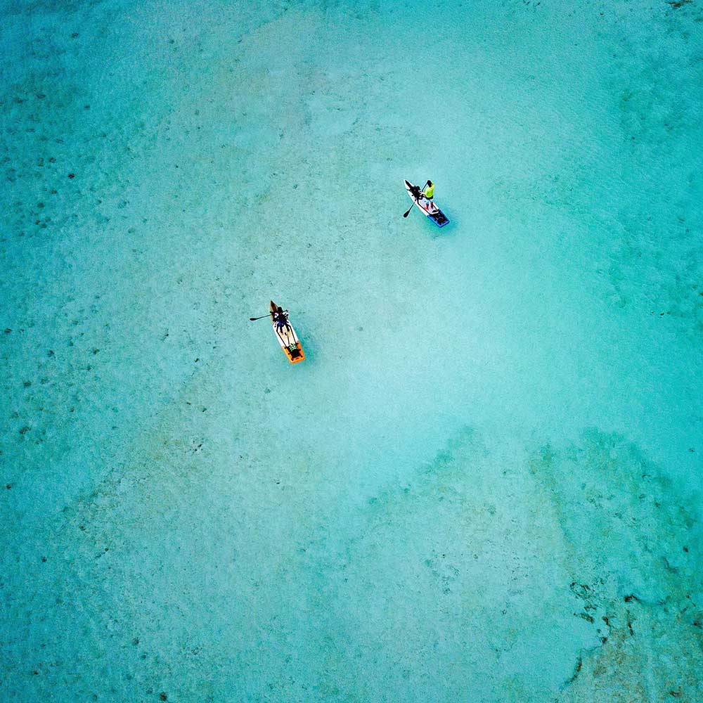 Areial image of two paddleboarders over blue waters