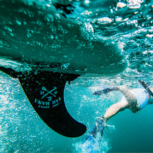 Underwater image of a paddleboard fin and a person swimming away from the paddleboard wearing flippers