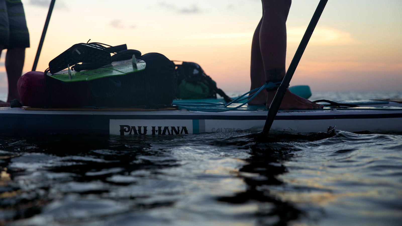 A close up image of someone paddleboarding, zoomed in at the board meeting the water