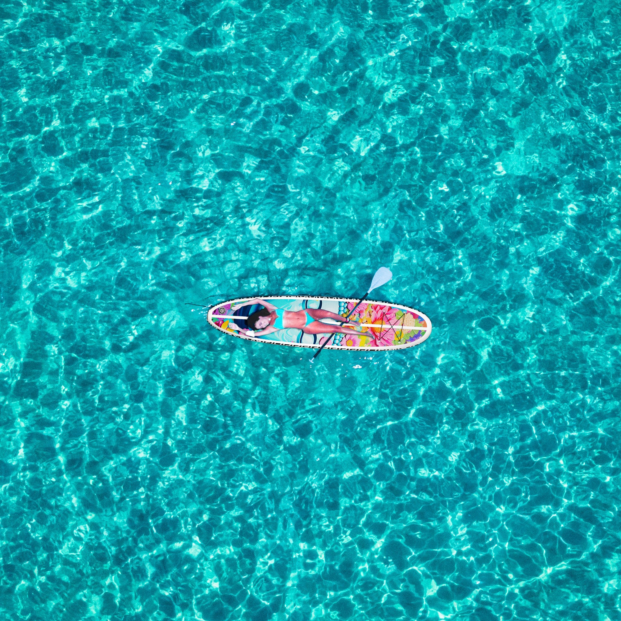 A woman lying on an inflatble paddleboard in the ocean